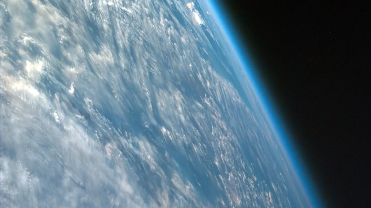A portion of the Earth's atmosphere, with clouds and the curvature of the planet visible.